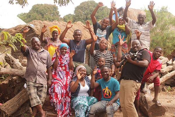 Tanzanian villagers involved in the grenadilla afforestation project smiling and waving.