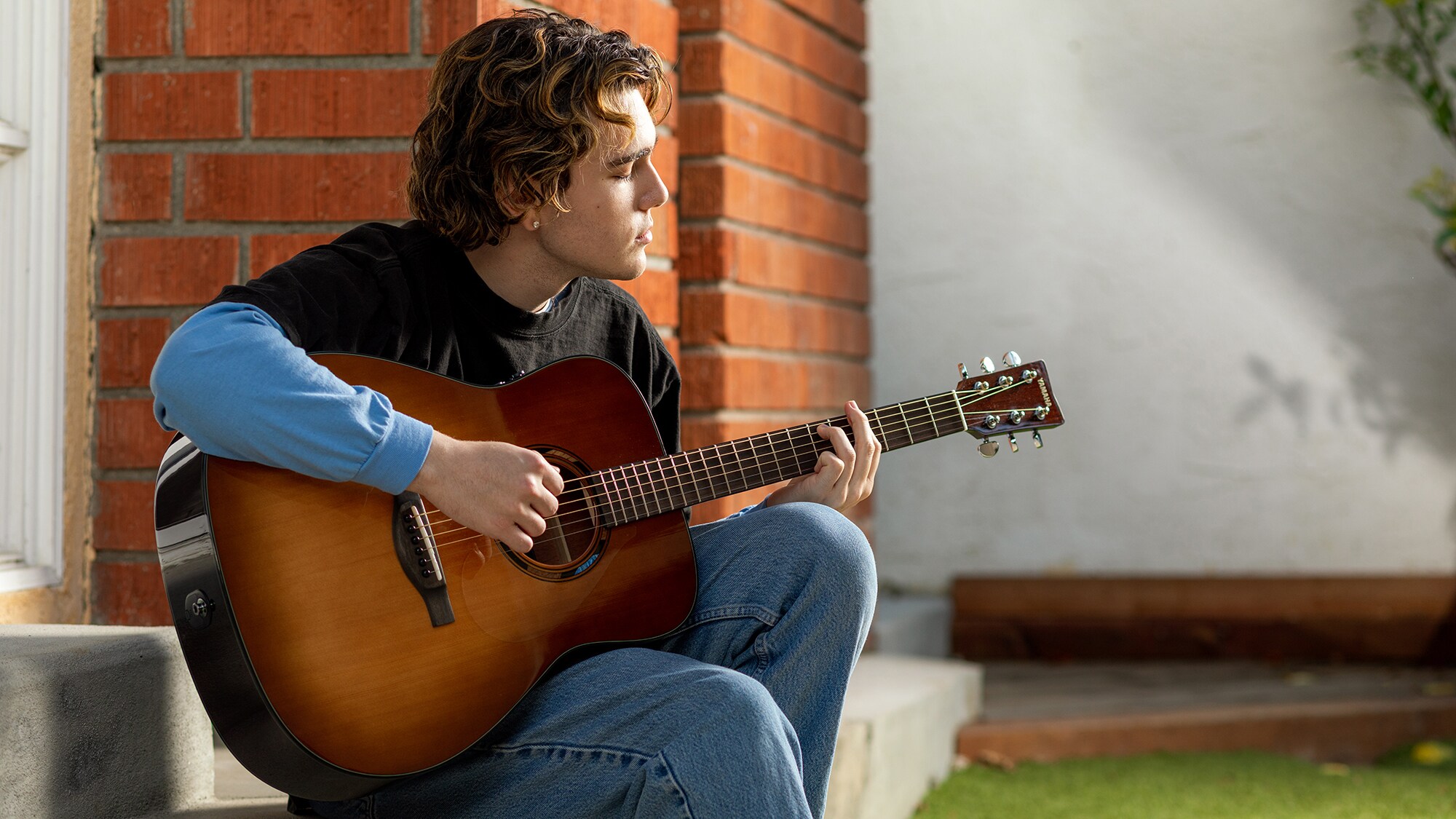 A man playing an TAG1E acoustic guitar outdoors