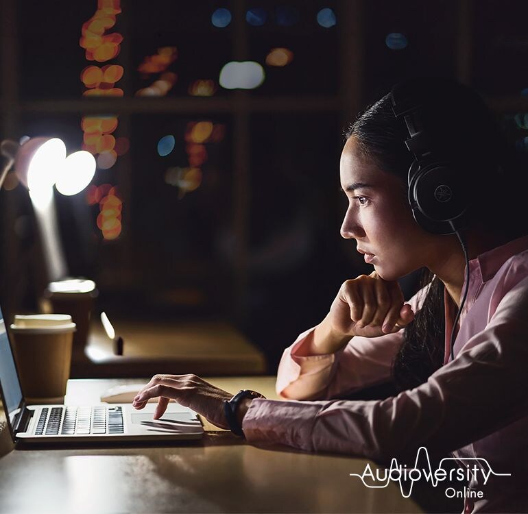 Key visual for Audioversity Online: a woman focused on an online training session.