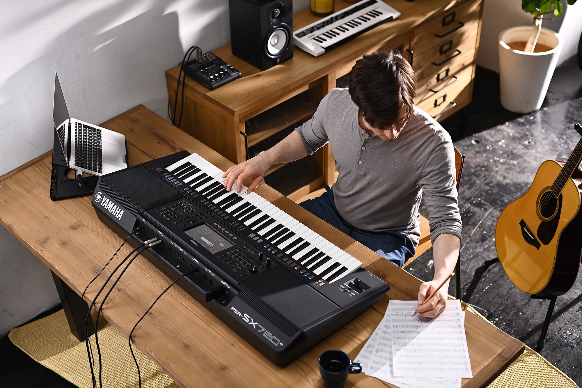 ภาพบุคคลหนึ่งกำลังเขียนบนโน้ตเพลงขณะเล่น Arranger Workstation PSR-SX720+ ของ Yamaha