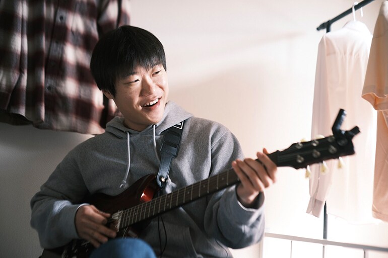 ชายคนหนึ่งพยายามเล่นกีตาร์เป็นครั้งแรก