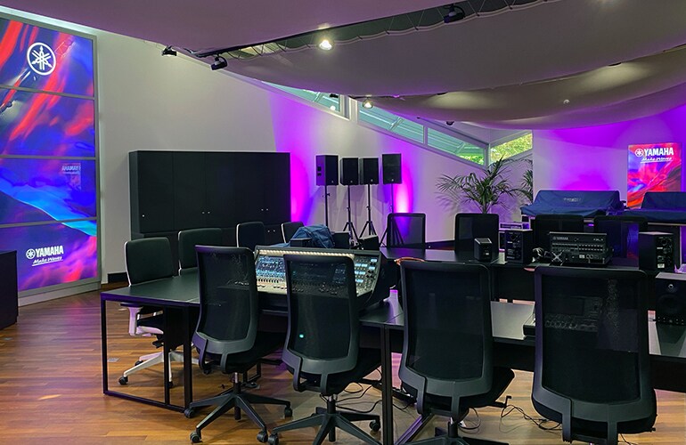 ภาพสถานที่ฝึกอบรมในครัวซี-โบบูร์ก พร้อมอุปกรณ์ระบบเสียงของ Yamaha หน้าจอแสดงผล และแสงไฟสีม่วง