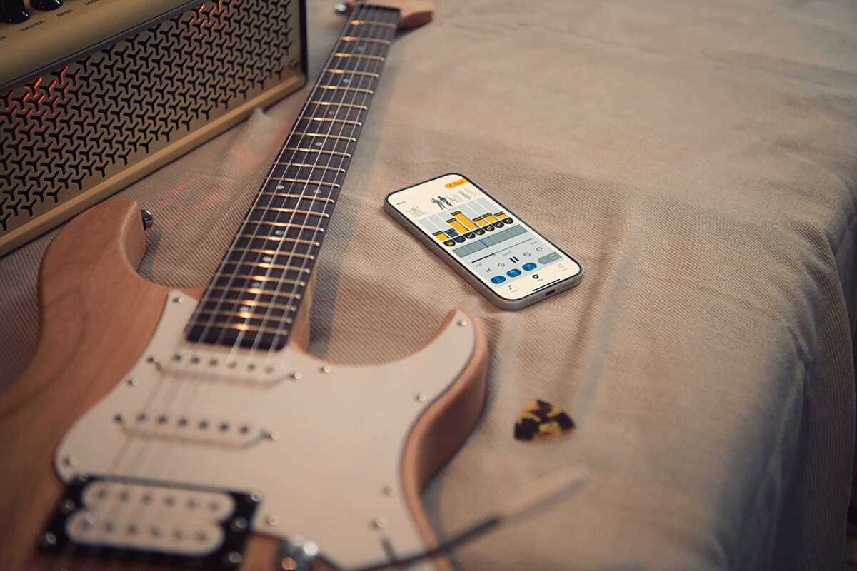 ภาพแอปฝึกซ้อมดนตรี Extrack อยู่ใกล้กับกีตาร์ไฟฟ้าและแอมปลิฟายเออร์
