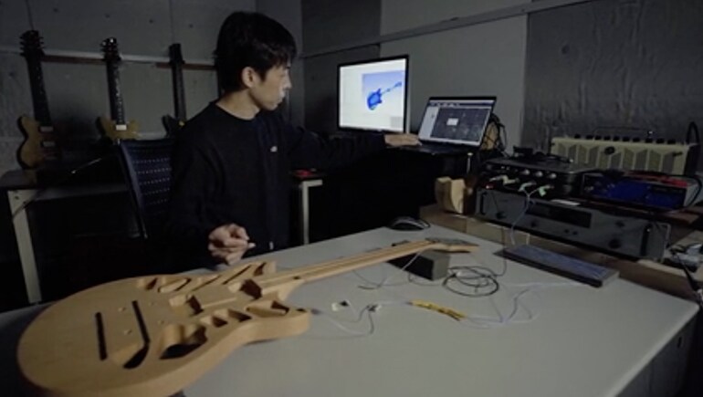 Research and development staff analyzing a guitar body with special equipment.